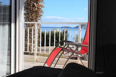 a red chair on a balcony with a view of the ocean at Apartments MARE BLU by the sea. in Porto Rafti