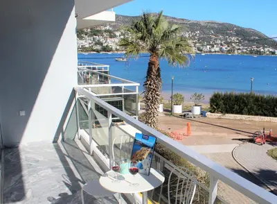 a balcony with a palm tree and a view of the ocean at Apartments MARE BLU by the sea. in Porto Rafti