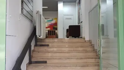 a hallway with stairs with a chair and a glass door at Palette Apartment Carmine - Athens Center, 6 BD, 3 BATH in Athens