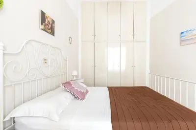 a bedroom with a white bed with a pink pillow at Beautiful appartment under Akropolis! in Athens
