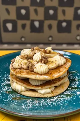 a stack of pancakes with ice cream and nuts on a blue plate at St. Bjur Suites in Athens