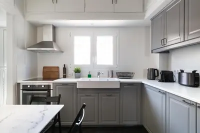 a kitchen with white cabinets and a sink and a table at Elegant Luminous 3BD apartment in Kolonaki by UPSTREET in Athens