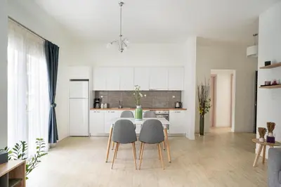 a kitchen with white cabinets and a table and chairs at Morum Athens Urban Stay in Athens