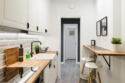 a kitchen with white cabinets and a sink and stools at Desirable 1BD Apartment in Kolonaki by UPSTREET in Athens