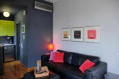 a living room with a black leather couch and red pillows at Homz AH03 Penthouse Studio Hilton Area in Athens
