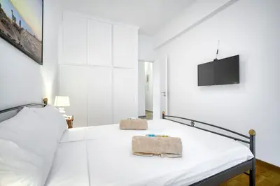 a white bedroom with a bed and a flat screen tv at Athens Alex Apartment in Athens