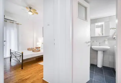 a white bathroom with a sink and a bed at Athens Alex Apartment in Athens