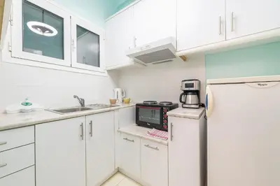 a small kitchen with white cabinets and a refrigerator at Athens Boutique Apartment by Cloudkeys in Athens
