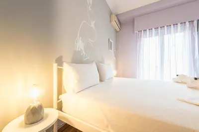 a white bedroom with a bed and a table with a lamp at Athens Boutique Apartment by Cloudkeys in Athens