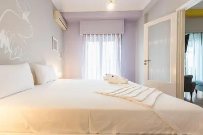 a large white bed with a teddy bear sitting on it at Athens Boutique Apartment by Cloudkeys in Athens