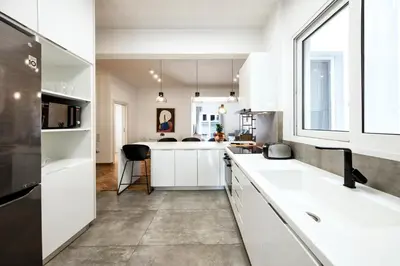 a kitchen with white cabinets and a large window at Kolonaki Square Executive Apartment in Athens