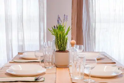 a table with plates and glasses and a potted plant at Maryflower Premium Apartments Piraeus in Piraeus