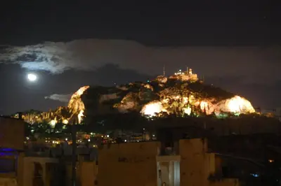 a mountain lit up at night with the moon on it at The Cactus Apartment with Large Sunny Balcony in Athens
