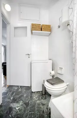 a white bathroom with a toilet and a door at The Cactus Apartment with Large Sunny Balcony in Athens