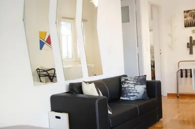 a living room with a black couch and mirrors at The Cactus Apartment with Large Sunny Balcony in Athens