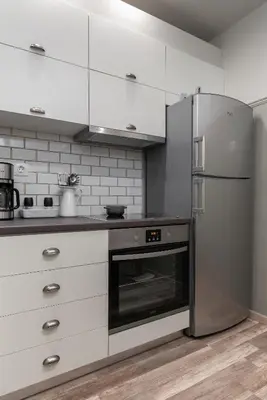 a kitchen with white cabinets and a stainless steel refrigerator at Αbsolute Athens VIII in Athens