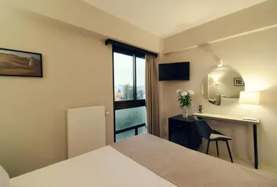 a hotel room with a bed and a desk and a window at Athens Iris Hotel in Athens