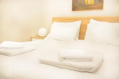 a white bed with two white towels on it at Neighborly Nest - Apartment in the heart of Athens in Athens