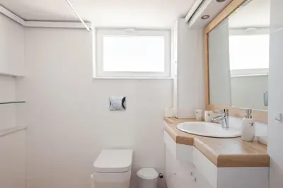 a bathroom with a sink and a toilet and a mirror at Elegant Athenian Apartment in Athens