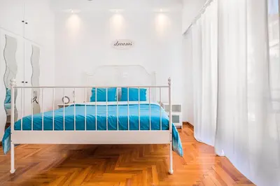 a white bed with blue sheets in a white room at Acropolis Exceptional View in Athens