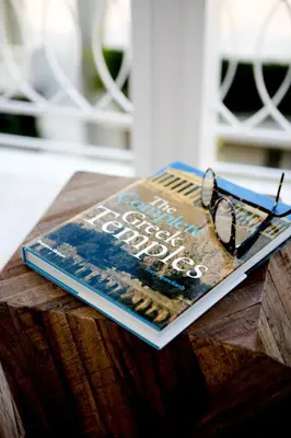 a book with glasses sitting on top of a table at Bluscapes Home in Athens