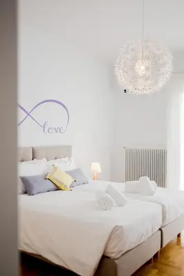 a bedroom with a large white bed with a chandelier at Bluscapes Home in Athens