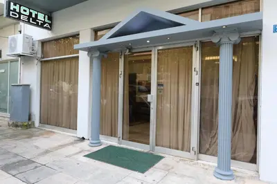 a building with glass doors with a blue roof at Athens Delta Hotel in Athens