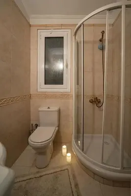 a bathroom with a toilet and a shower with candles at Nostalgia Seaview House in Anavissos