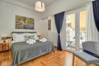 a bedroom with a bed and a chair and a window at Acropolis Plus Penthouse in Athens