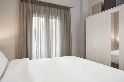 a white bedroom with a bed and a window at Charming 1bd Apt at Concert Hall in Athens