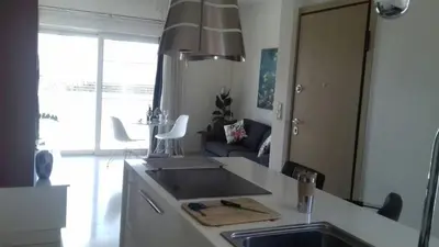 a kitchen with a sink and a living room at Athens riviera modern and elelegant flat 500 metres from VOULA beach in Athens