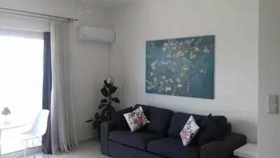 a living room with a blue couch and a painting at Athens riviera modern and elelegant flat 500 metres from VOULA beach in Athens