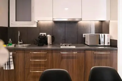 a kitchen with wooden cabinets and a sink and a microwave at TONI'S Cute 2BD Apartment in Koukaki! in Athens