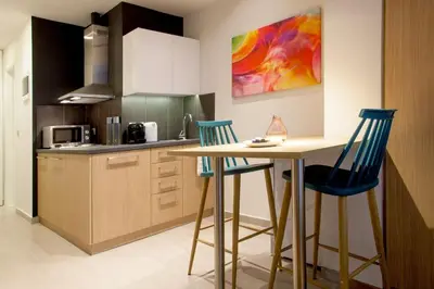 a kitchen with a table and two blue bar stools at TONI'S Fashionable Studio near Presidential Garden in Athens