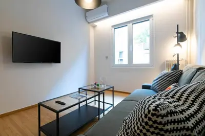 a living room with a couch and a tv at TONIS Le Petit Nicolas 1BD Apartment in Koukaki! in Athens