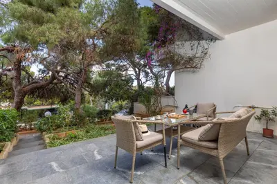 a patio with a table and chairs and trees at Secret Aktis by BluPine in Athens