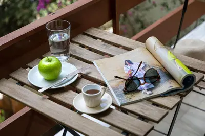a table with a book and an apple and a cup of coffee at Secret Aktis by BluPine in Athens