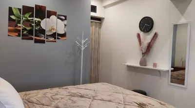 a bedroom with a clock and paintings on the wall at MOTEL KATERINA in Keratea