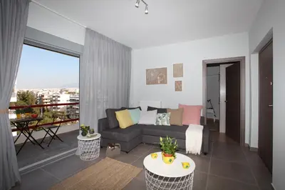 a living room with a couch and a balcony at Edem Beach Apartment with Mountain View by Athenian Homes in Athens