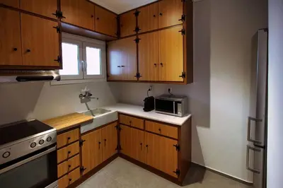 a kitchen with wooden cabinets and a sink and a microwave at Seaside Renovated Top Floor Apartment in Saronida
