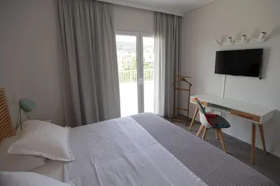a bedroom with a bed and a desk and a television at Seaside Renovated Top Floor Apartment in Saronida