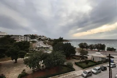 a city with cars parked on a street next to the ocean at Seaside Renovated Top Floor Apartment in Saronida