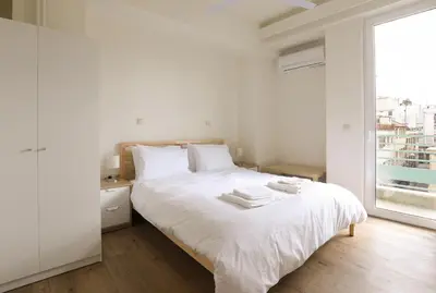 a white bedroom with a white bed and a window at MADONAS HOUSE PSIRI in Athens