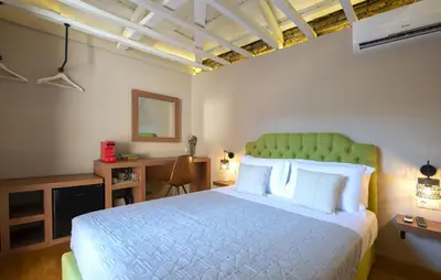 a bedroom with a bed with a green headboard and a desk at Metis Athens Suites in Athens