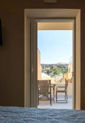 a bedroom door open to a patio with a table and chairs at Metis Athens Suites in Athens