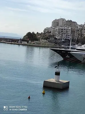 a bird sitting on a block in the water next to a boat at ATHENS RIVIERA SEA VIEW APARTMENT in Piraeus