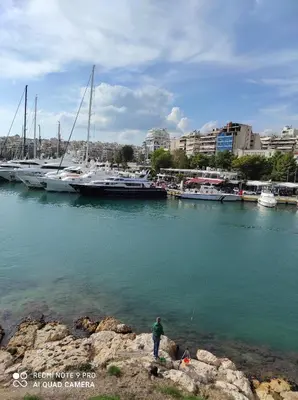 a man standing in the water near a marina with boats at ATHENS RIVIERA SEA VIEW APARTMENT in Piraeus