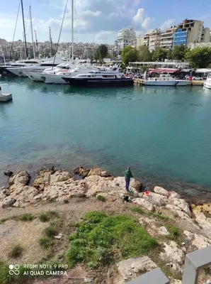 a man standing on the shore of a marina with boats at ATHENS RIVIERA SEA VIEW APARTMENT in Piraeus