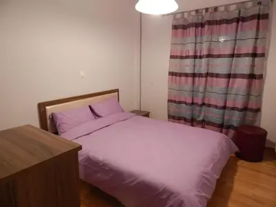 a bedroom with a bed with purple sheets and a window at ATHENS RIVIERA SEA VIEW APARTMENT in Piraeus