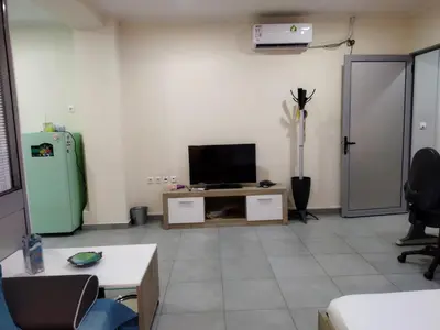 a living room with a television and a refrigerator at Cozy apartment near to the airport in Kouvarás